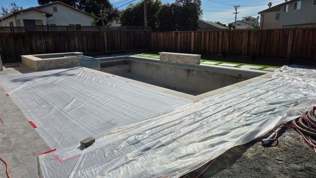 Pool deck covered to prepare for pebble resurfacing the pool and spa